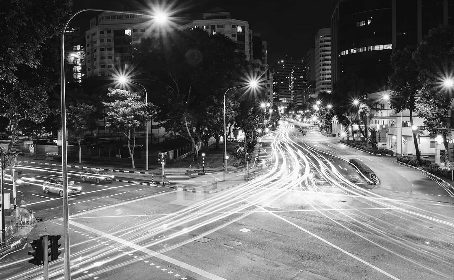 Black and white image of busy traffic intersection at night.
